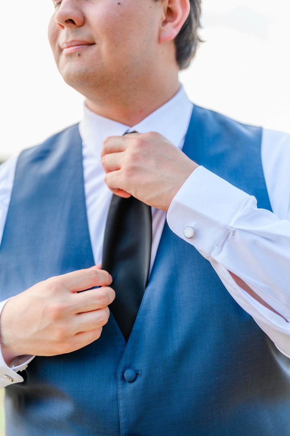 Close-up details of groomsmen adjusting their collars and ties.