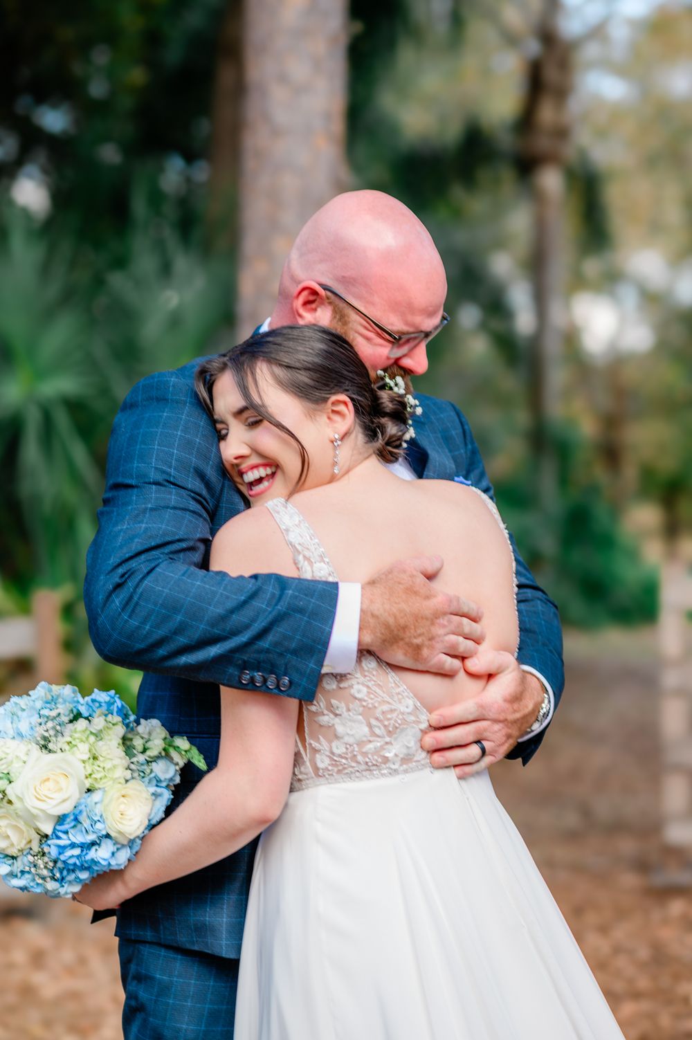 A tender moment captured between newlyweds embracing outdoors in a wooded setting.