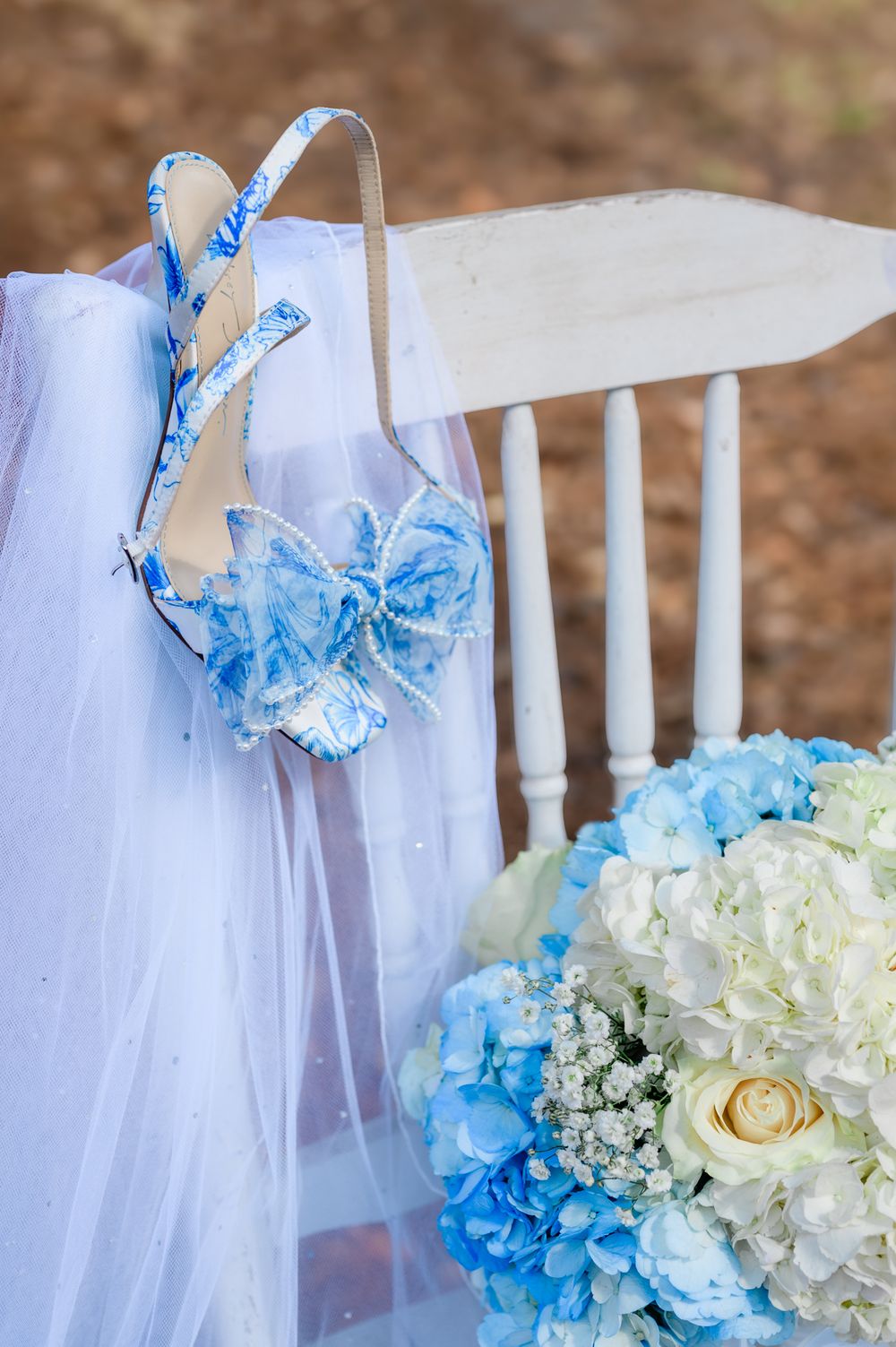 Wedding chair decorations featuring blue and white hydrangeas with delicate fabric draping.