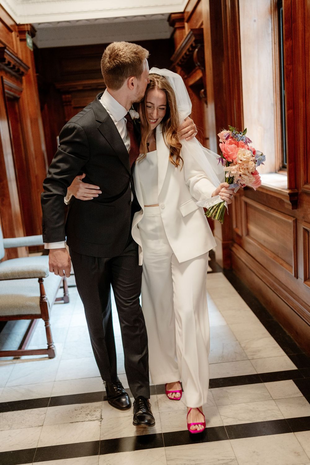 A couple in wedding attire share intimate moments in a sequence of photos along a hallway with wooden paneling.