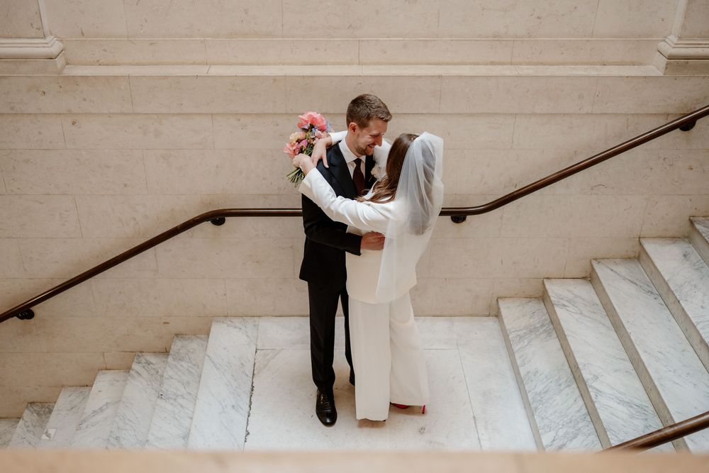 A couple shares an intimate moment on marble stairs during their wedding ceremony.