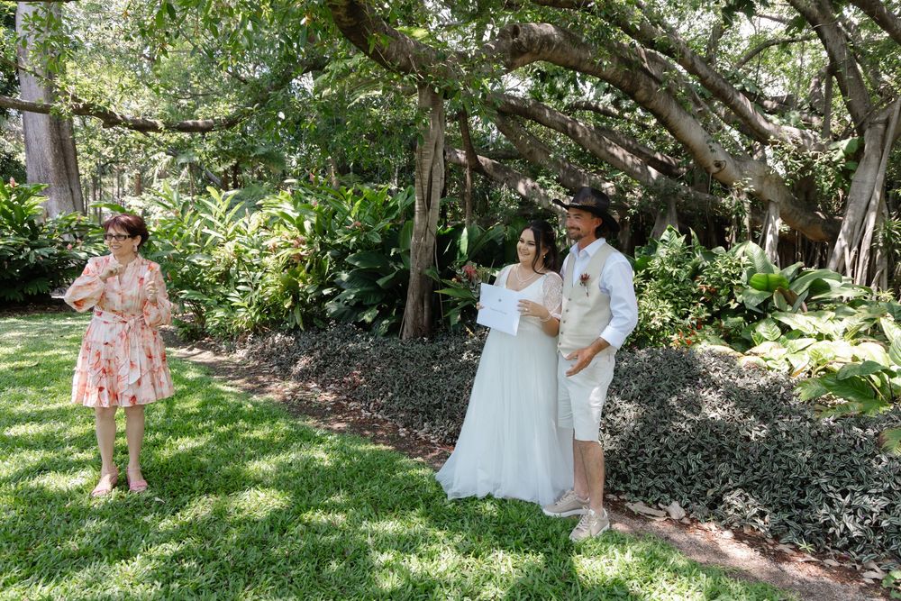 Couple shares intimate moments in a lush garden setting with sunlight filtering through trees.