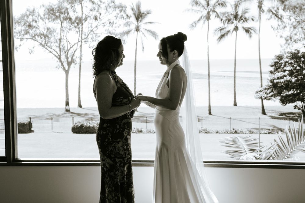 A series of black and white wedding photos showing intimate moments between couples in a beachside setting.
