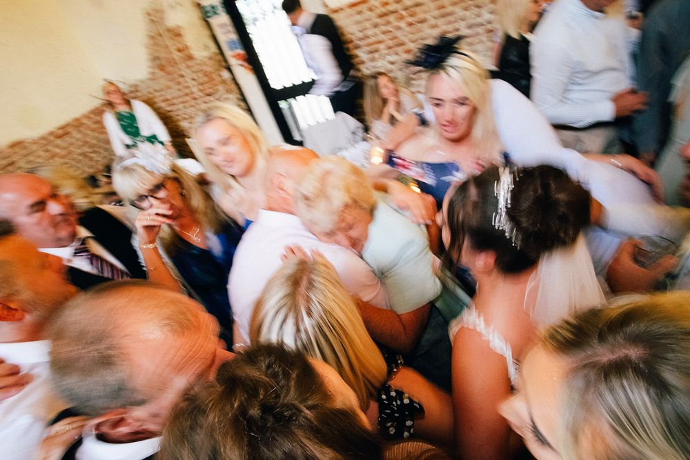 A blurred motion shot of people dancing and celebrating at a lively party or wedding reception.