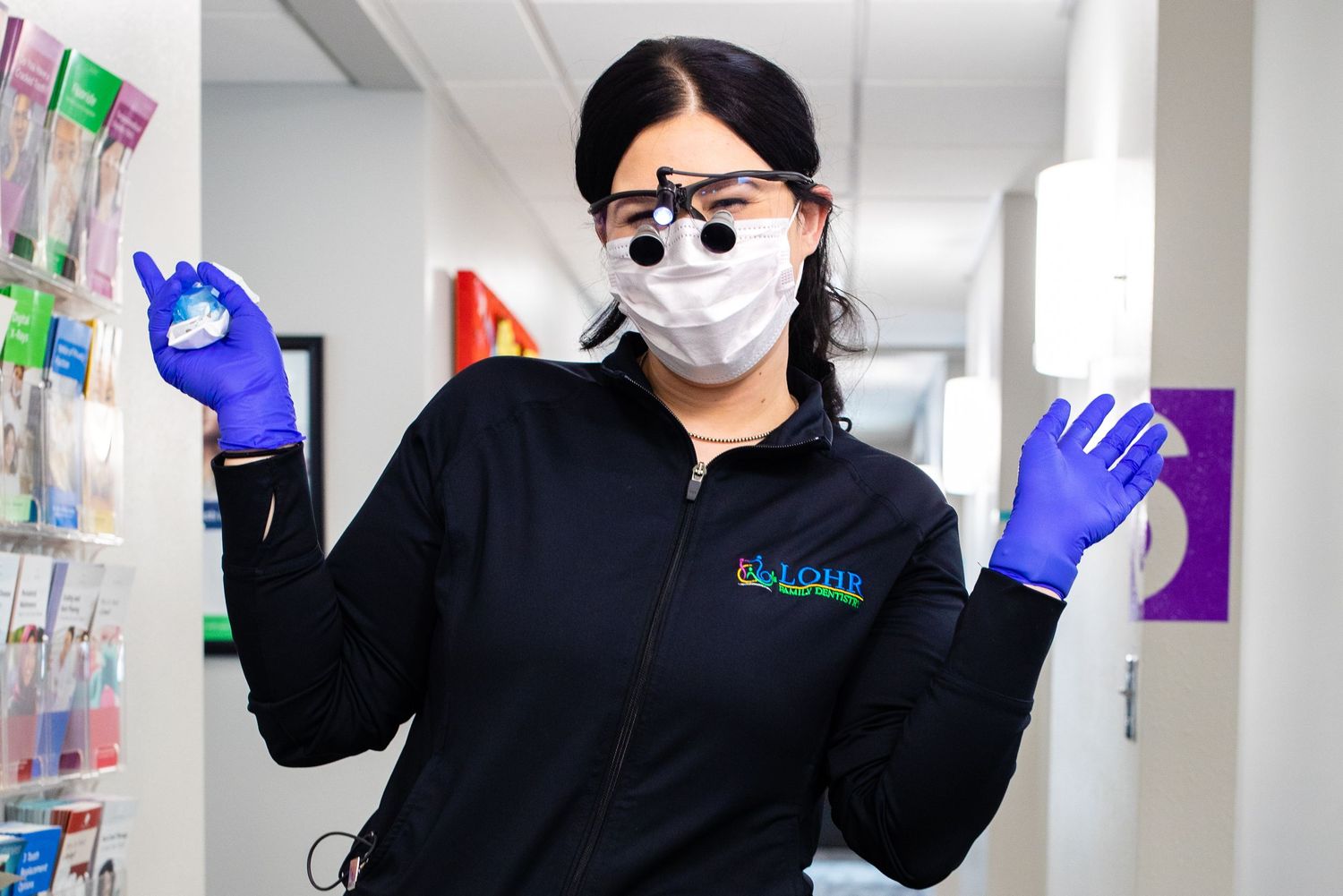 Business branding session of dental hygienist wearing protective mask and latex gloves gesturing while working in a dental office.