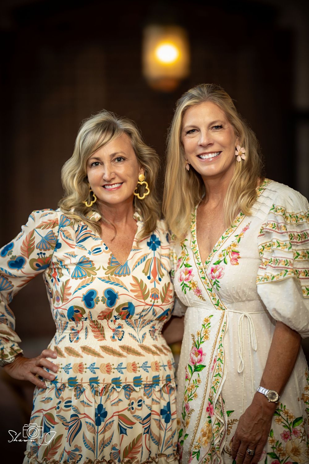 Two people wearing matching floral embroidered dresses pose together in a series of candid photos.