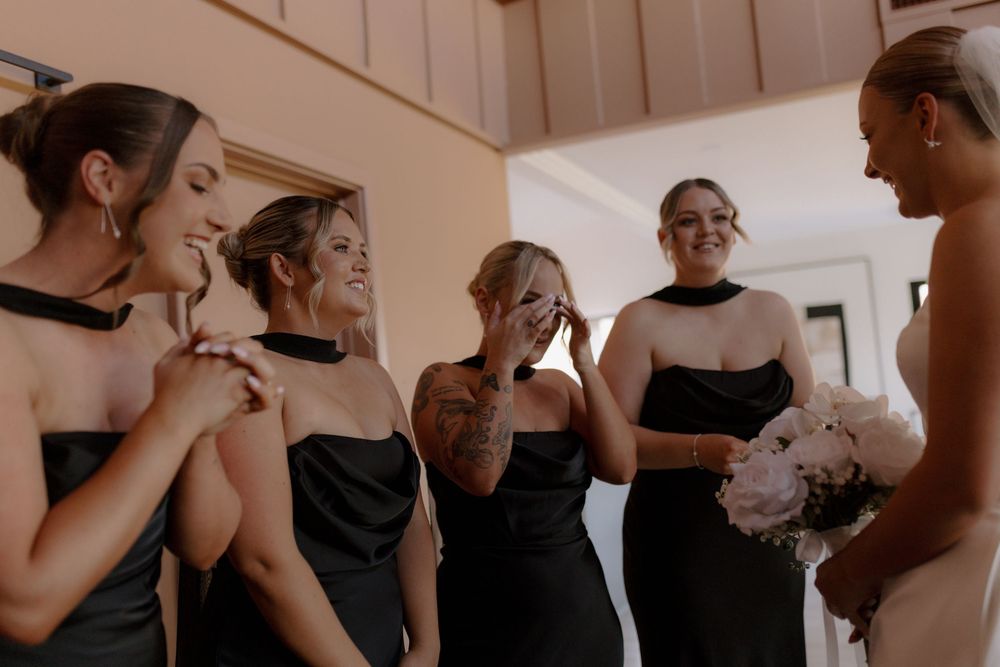 A group of people in black and white attire gather in a warm-toned indoor space during a social event.