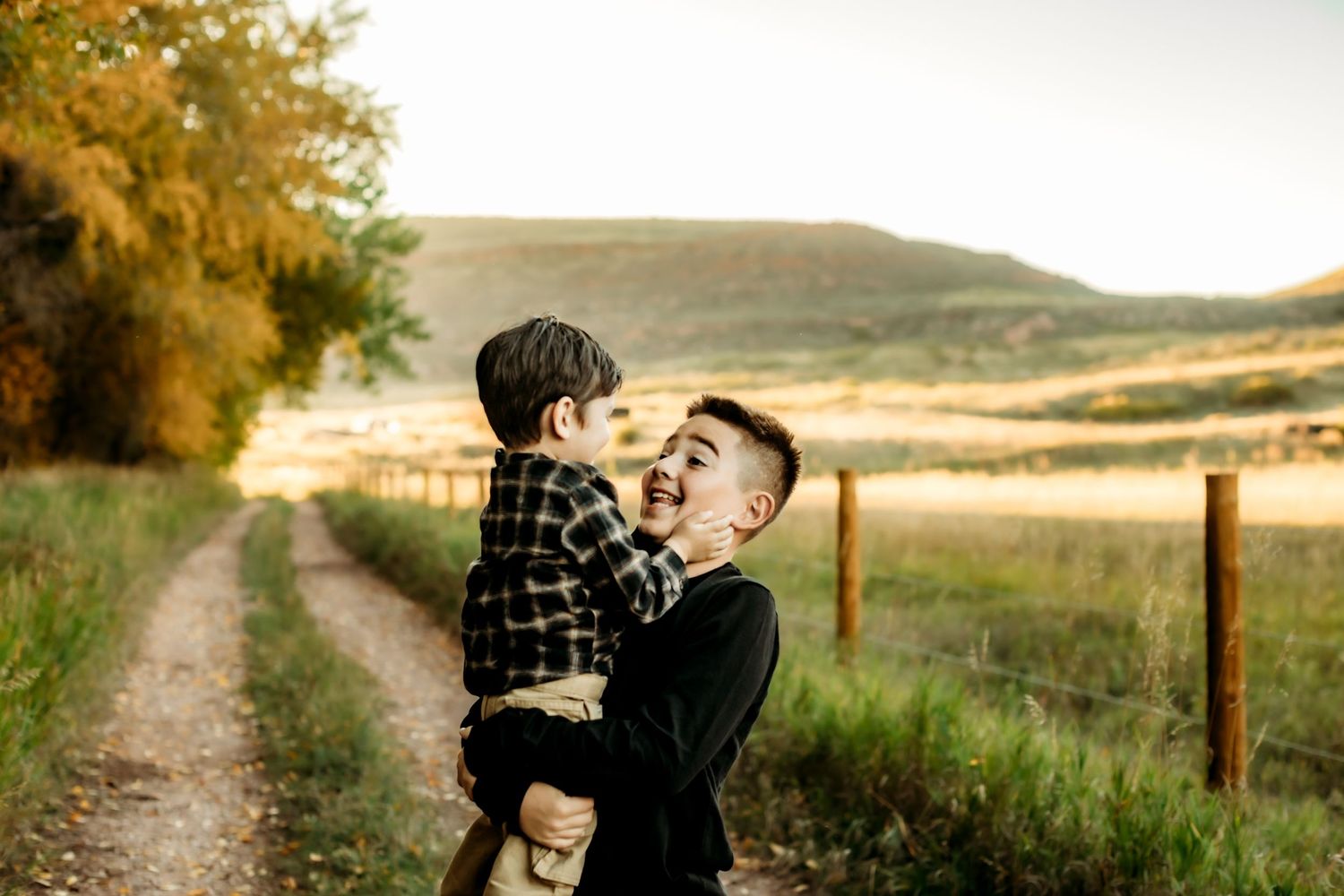 A joyful moment shared between two people on a dirt path with rolling hills and autumn trees in the background.