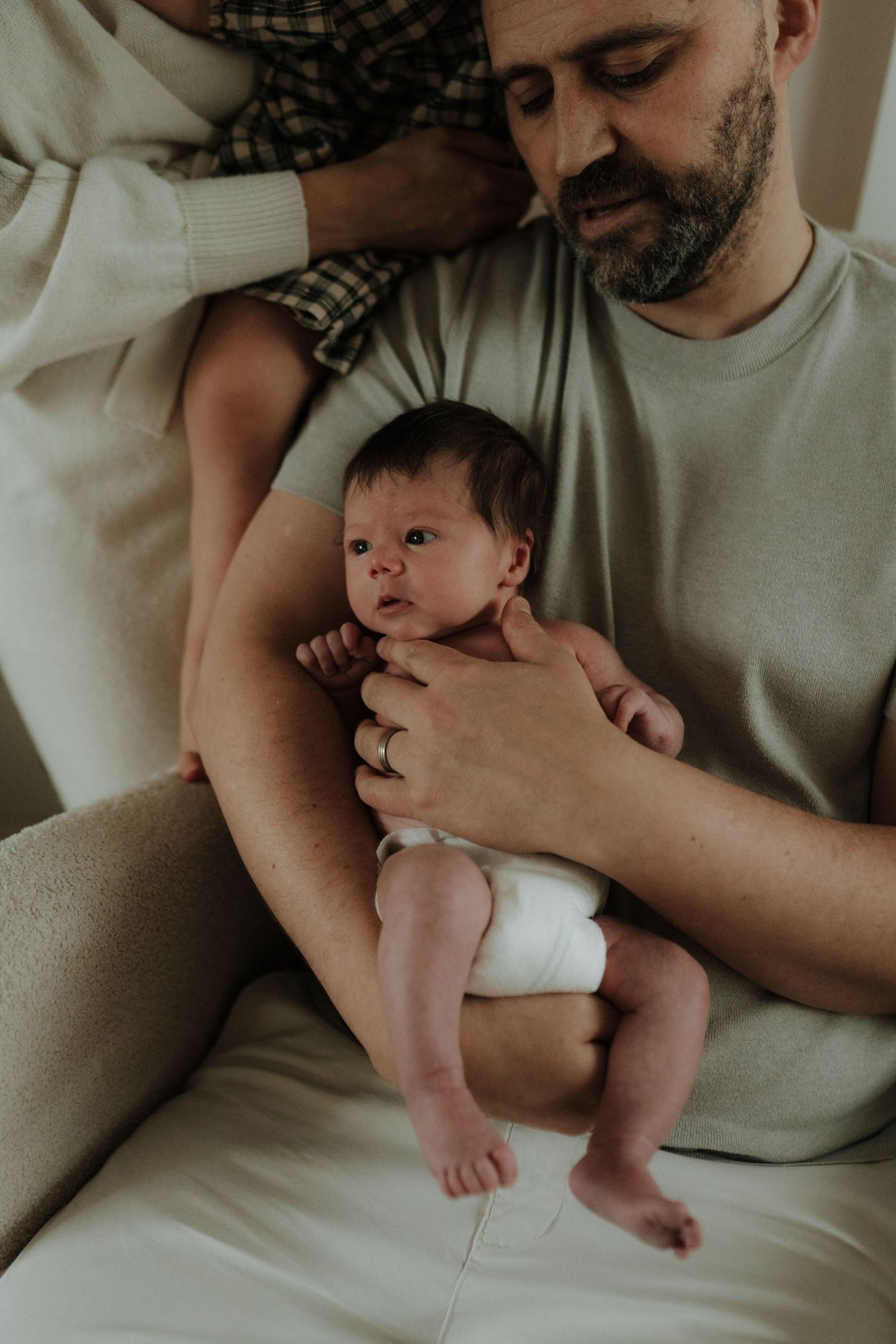 A tender moment between a parent and newborn baby lying on white bedding in a series of connected photos.