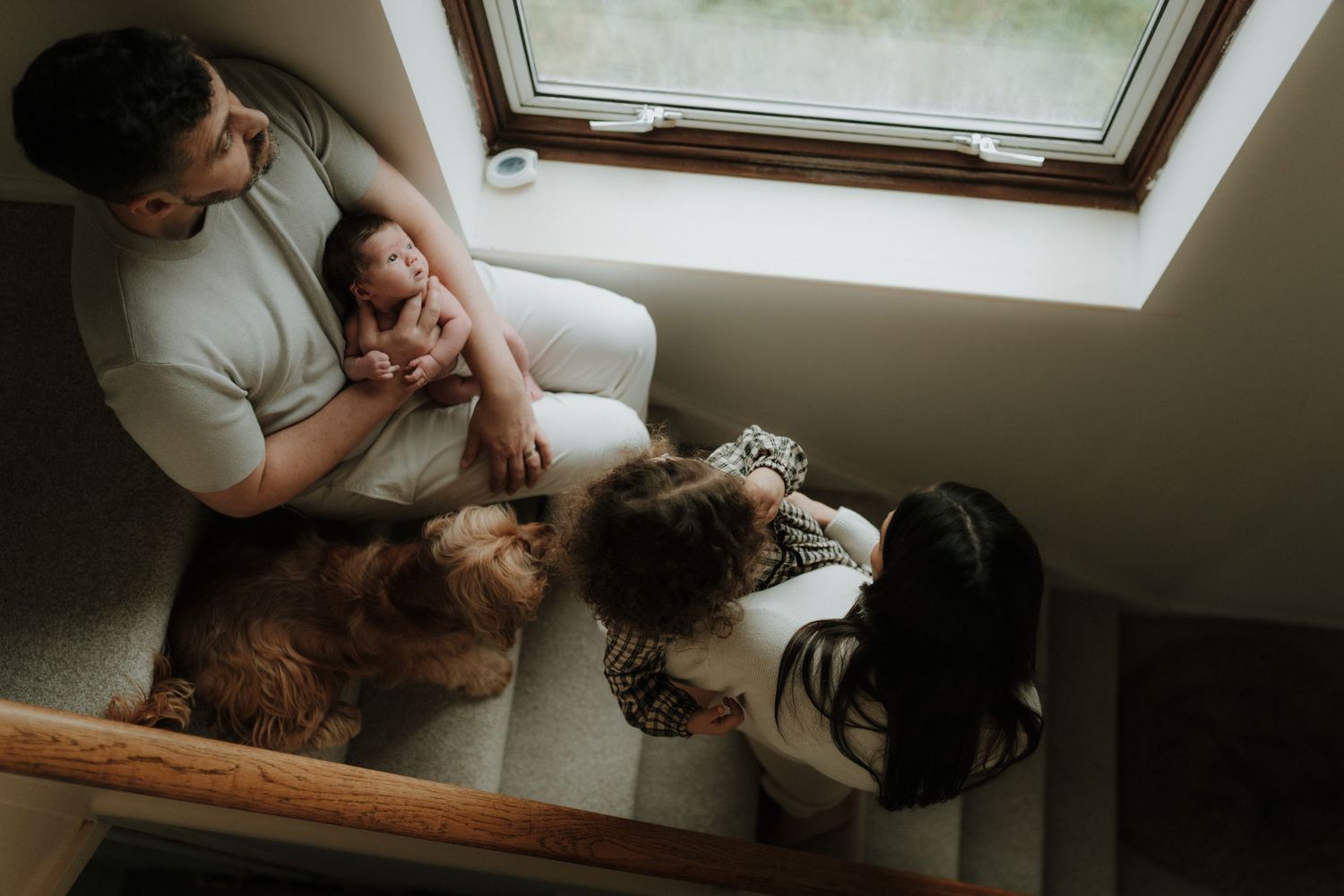 A tender moment captured in a window seat showing affectionate interaction between people in natural light.