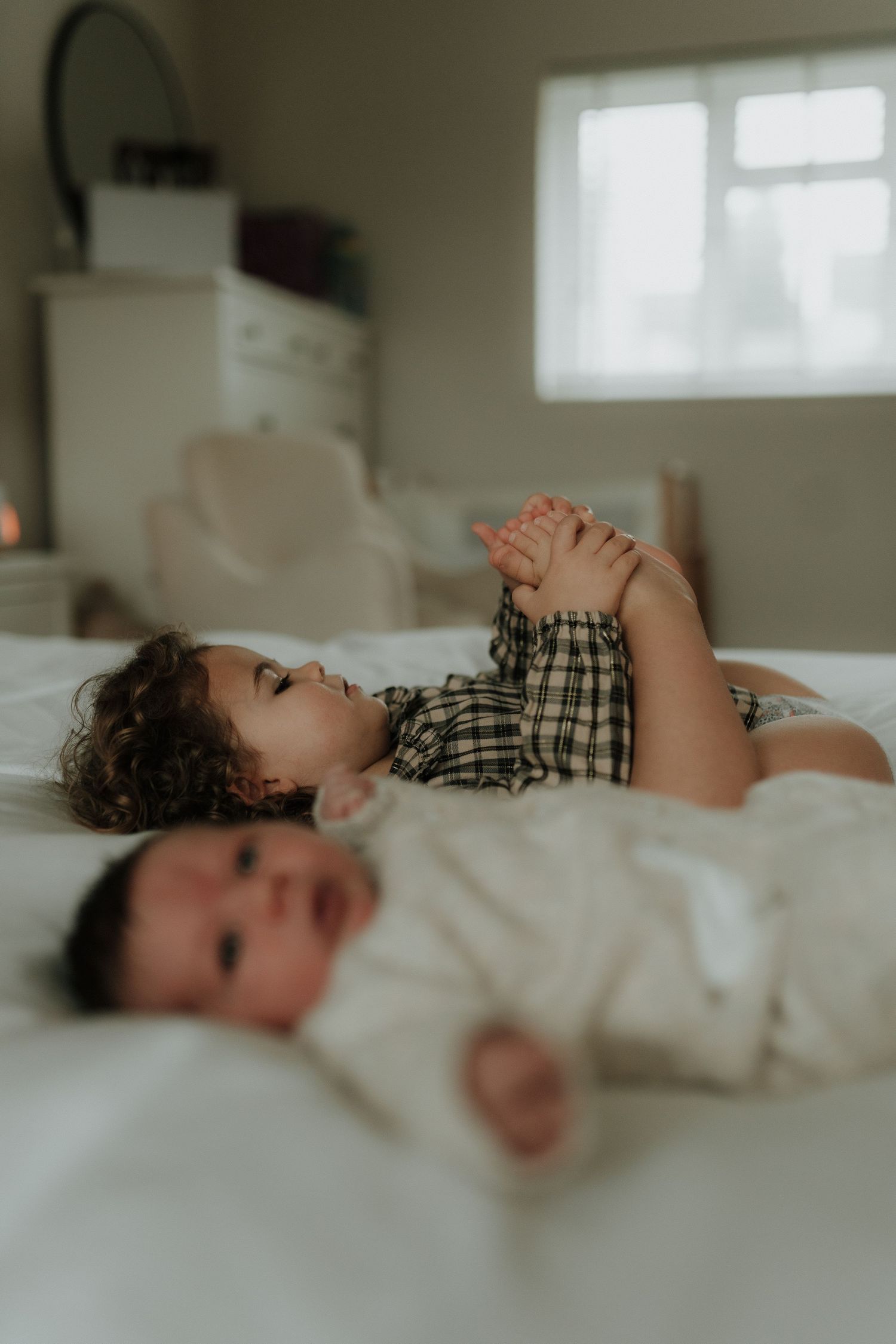 A series of four soft-focus photos showing a young child lying on white bedding in a plaid shirt.
