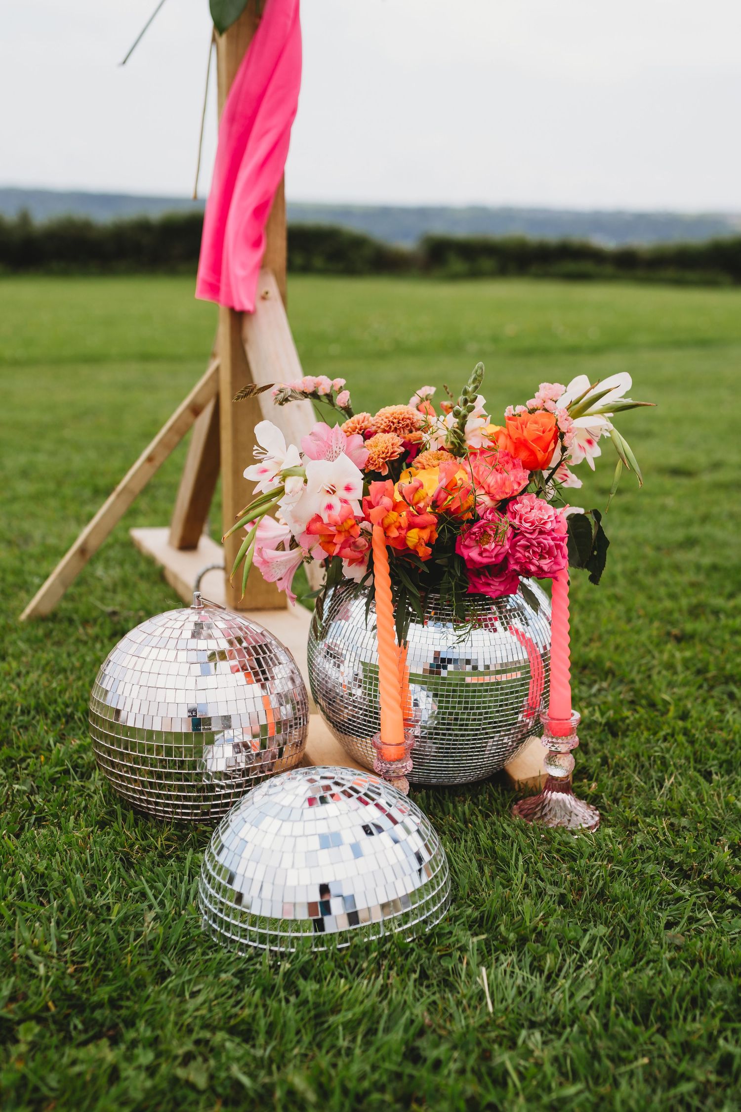 Colorful wedding bouquet with roses and tulips resting against a vintage car wheel.