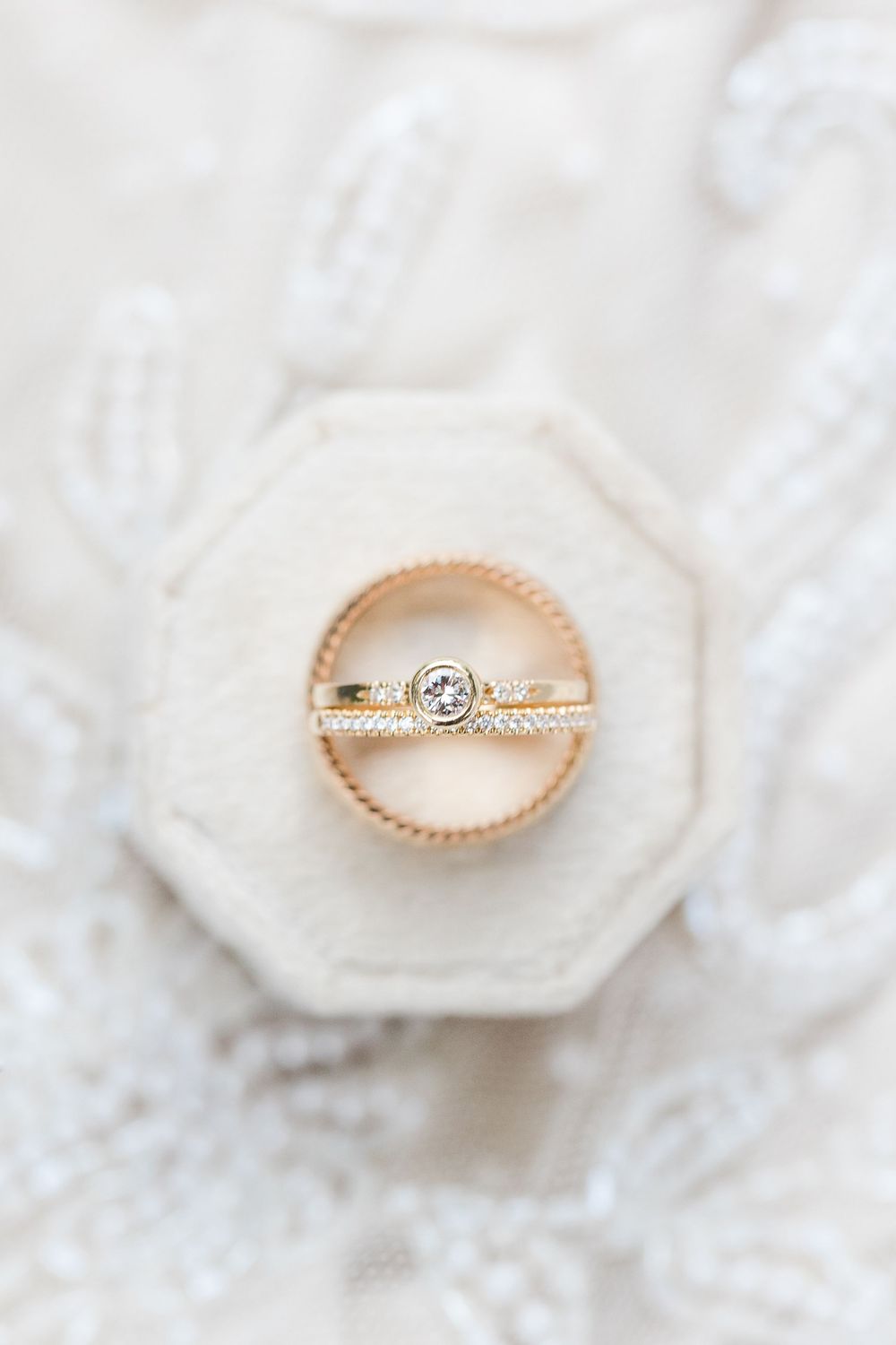 Delicate rose gold engagement ring with diamond solitaire on white textured surface.