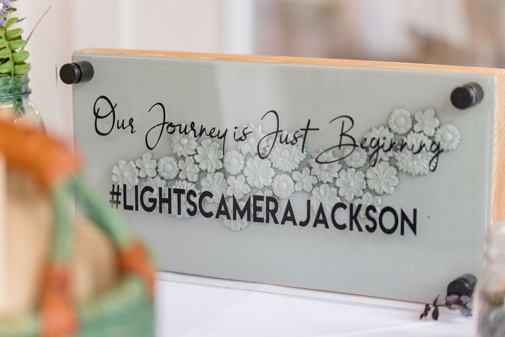 A decorative wall sign with 'Lights Camera Jackson' text mounted on a white surface with honeycomb pattern details.