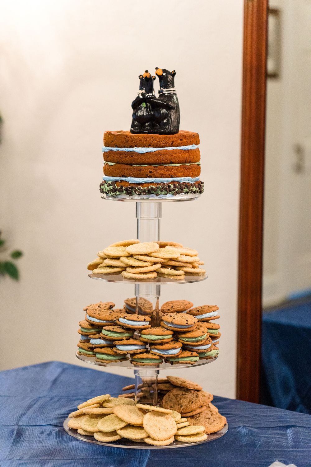 Multi-tiered dessert stand displaying chocolate chip cookies and sugar cookies topped with a small cake decoration.