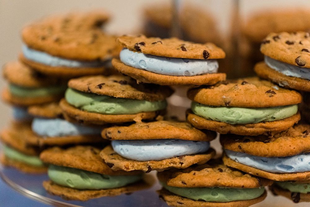 Chocolate chip cookie sandwiches filled with mint green and white cream frosting stacked on a plate.