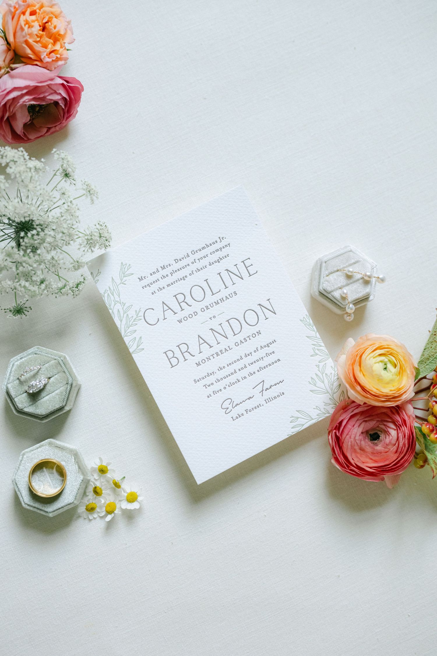 Elegant white wedding place cards with calligraphy text arranged with peach and pink ranunculus flowers on light background. - Lake Forest