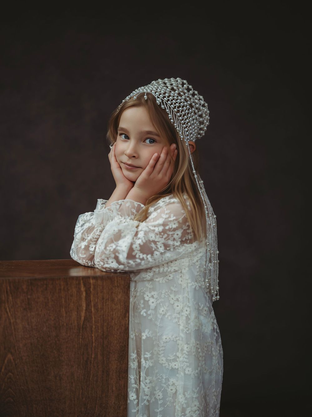 A series of artistic portraits showing a child in a delicate white lace dress against a dark background.