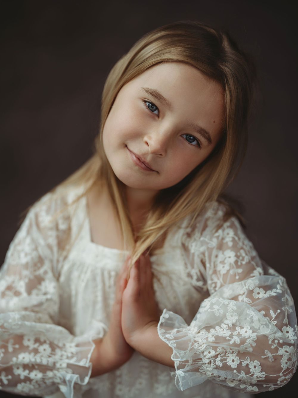 A collection of dreamy portraits featuring a child wearing an elegant white lace dress in moody lighting.