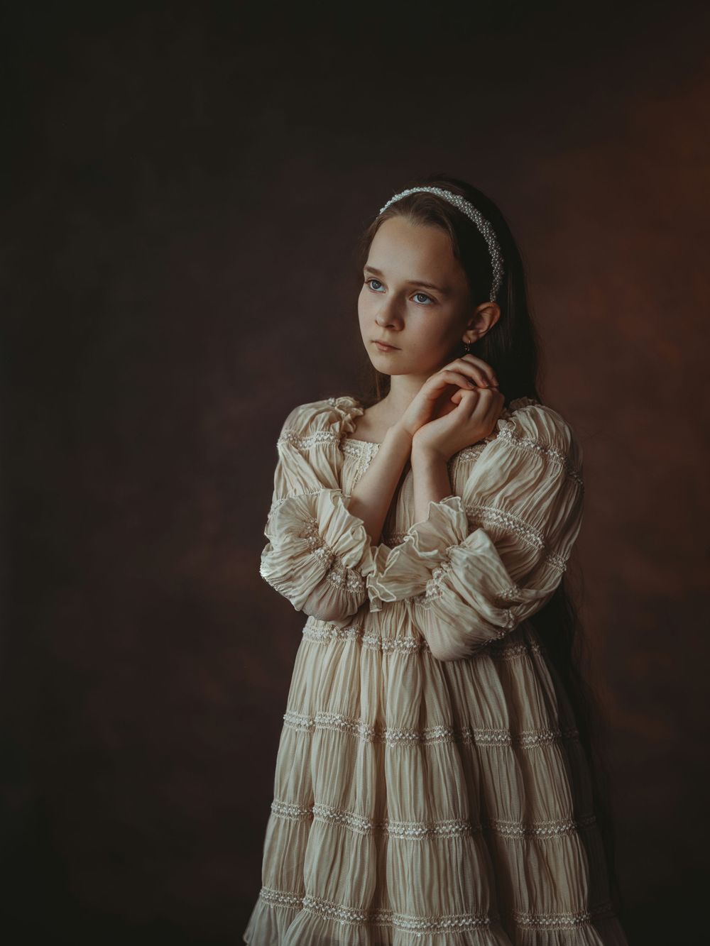 Artistic portrait of a figure in a vintage white lace dress against a dark moody background.