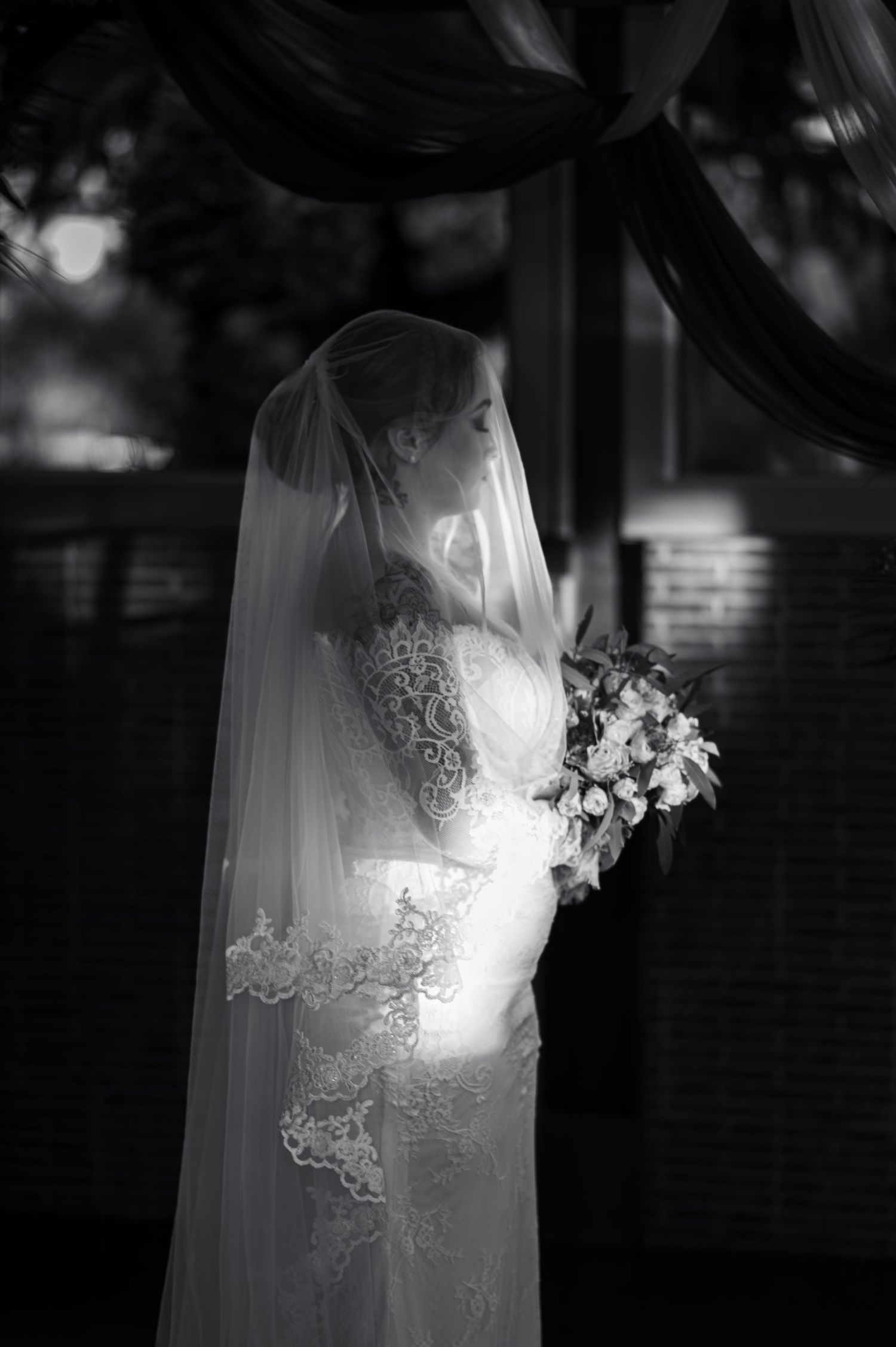 Une photographie de mariage romantique en noir et blanc montrant des détails délicats en dentelle sur un voile de mariée fluide.