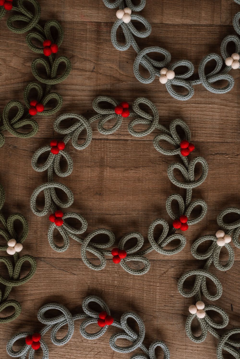 Decorative rope design with red flowers creates an elegant pattern against dark wooden background.