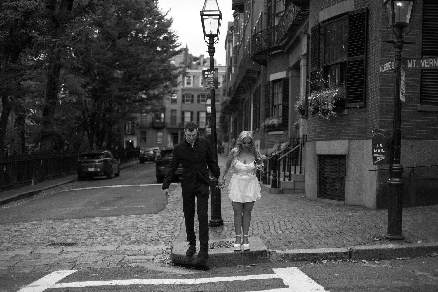 A black and white street scene shows cobblestone roads and historic buildings with lamp posts in Boston's Beacon Hill.