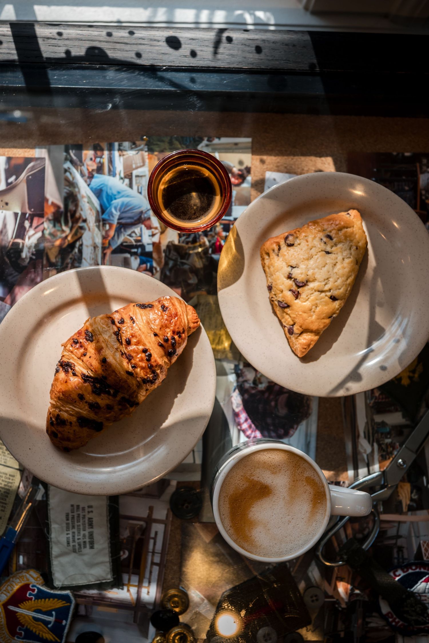 Chocolate chip cookies and coffee cups arranged on white plates in a dark, moody cafe setting.
