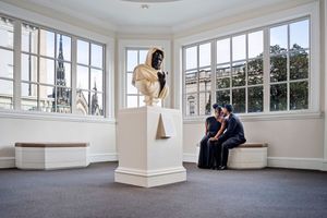 A bright sunlit corner room with large windows and white walls showing architectural details and interior features.