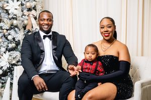 Elegant family in formal attire poses together in front of a white Christmas tree during holiday photoshoot.