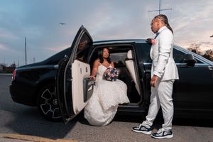A black limousine parked at sunset with people entering and exiting the vehicle during a formal event.