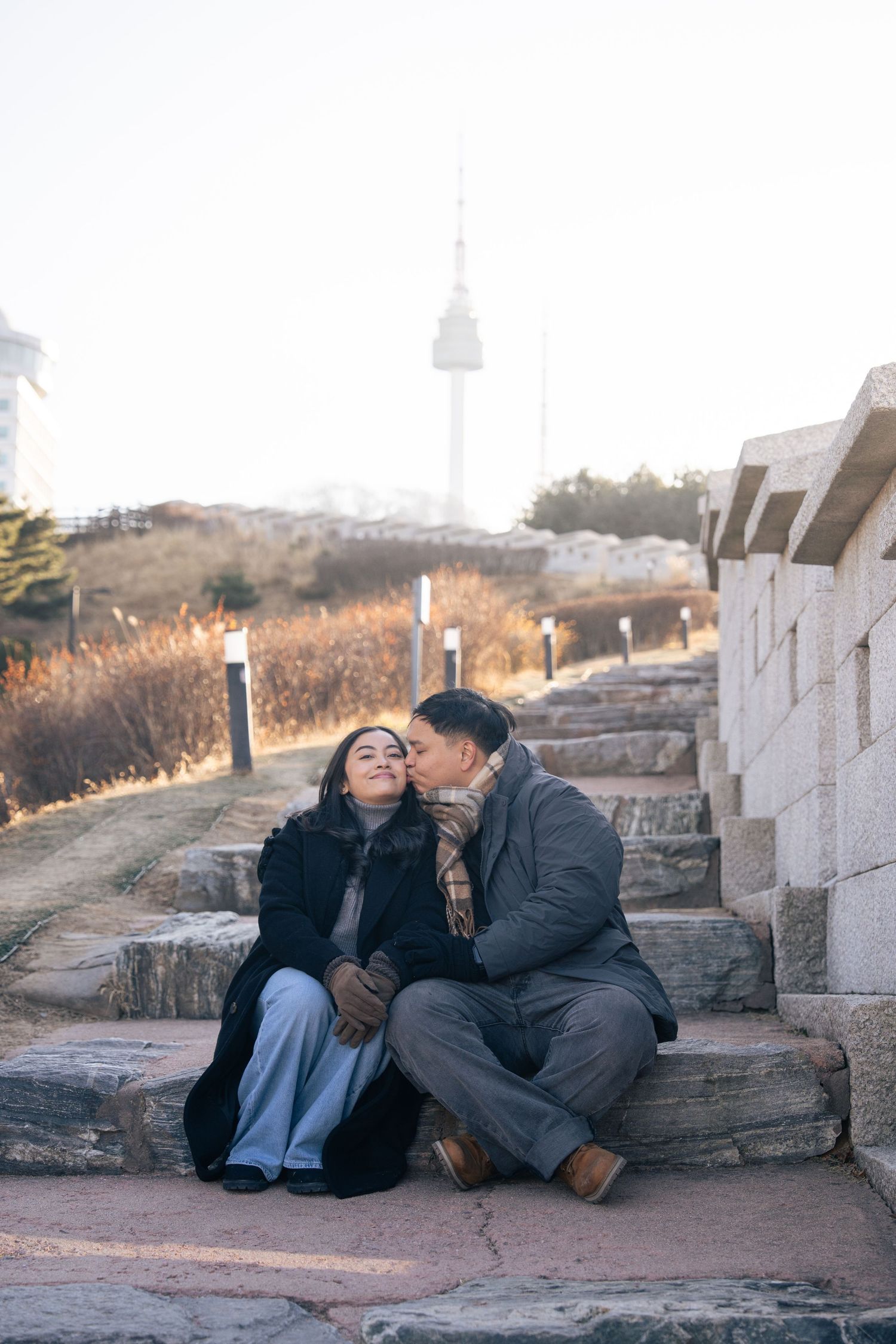 A couple sits together on stone steps at sunset sharing an intimate moment outdoors.