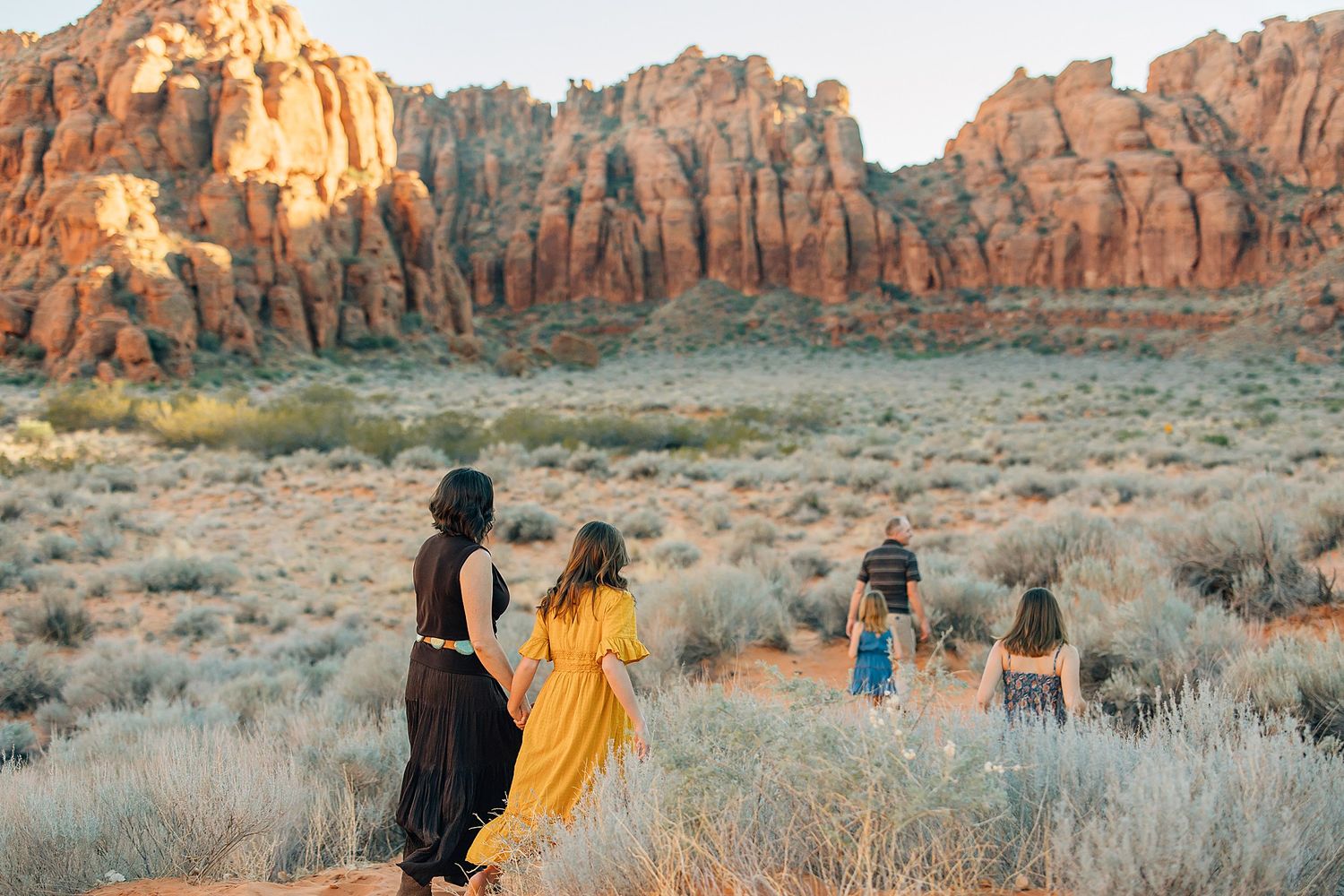 Group explores scenic red rock formations and desert landscape during golden hour at Arches National Park.
