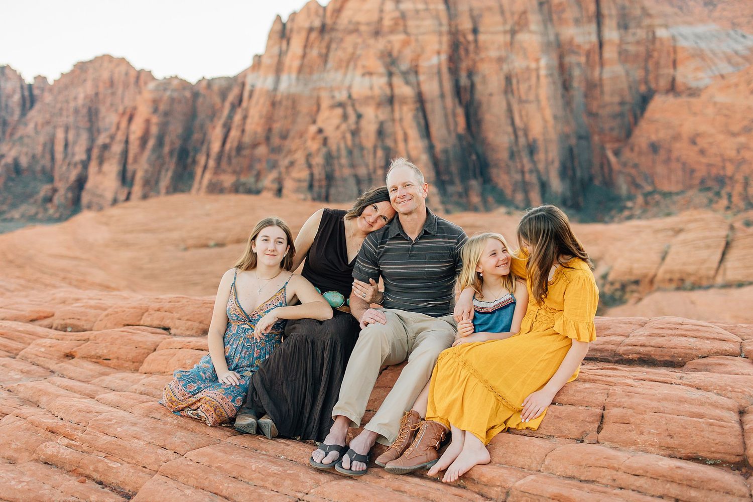 Group sitting together on red rock formations at sunset in Snow Canyon State Park, Utah.