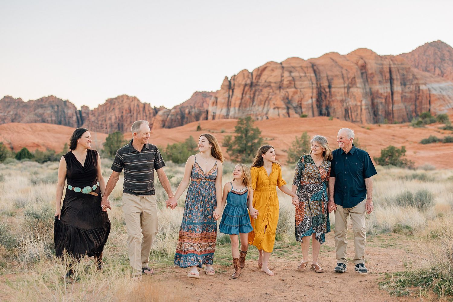 A group of people walking together and laughing against a backdrop of red rock formations in the desert.