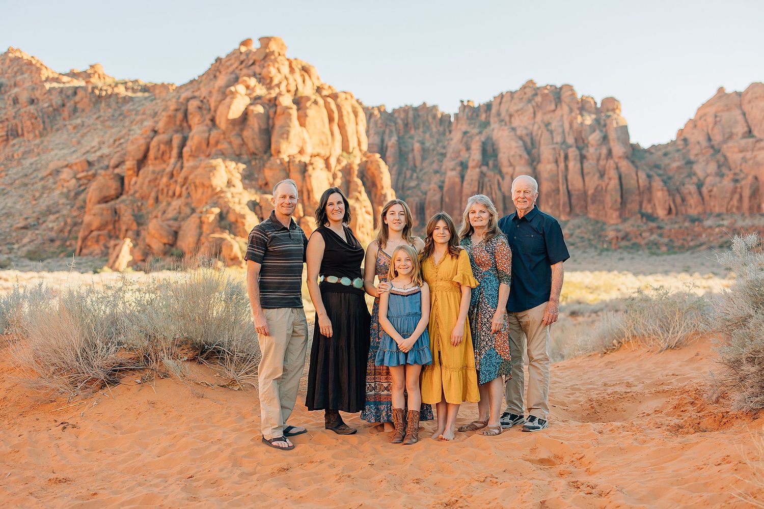 A group poses together against stunning red rock formations at sunset in Snow Canyon State Park, Utah.