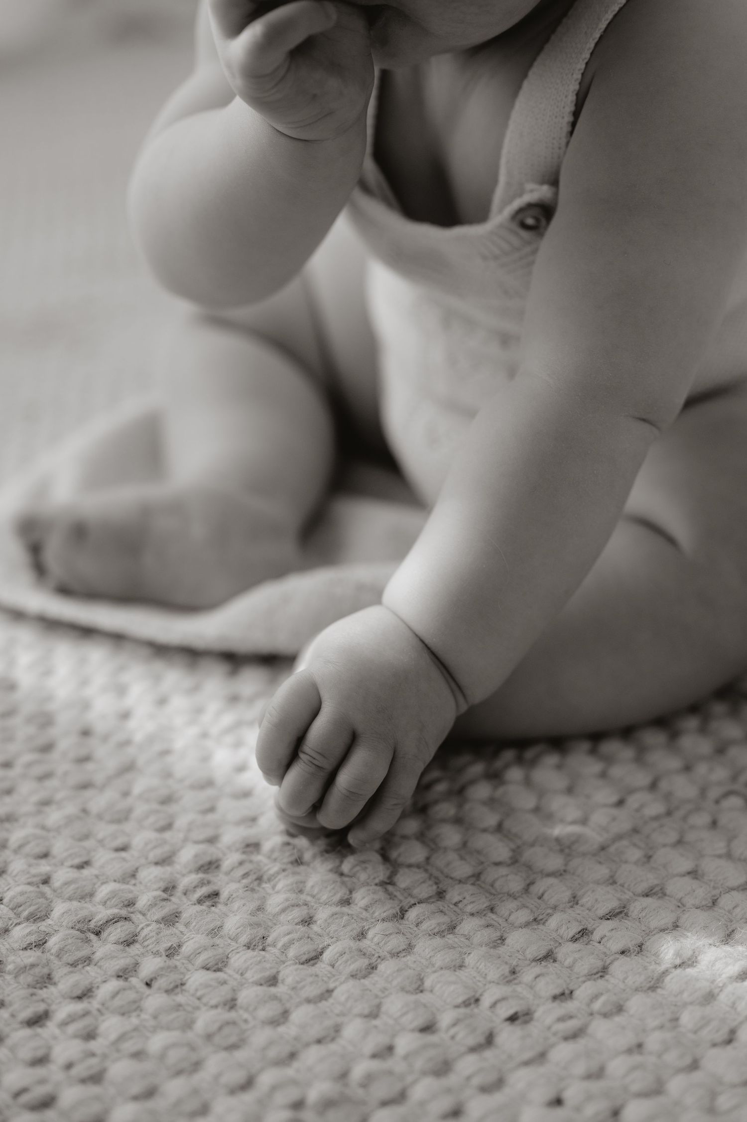 Close-up black and white photo of tiny baby toes on textured carpet or rug.
