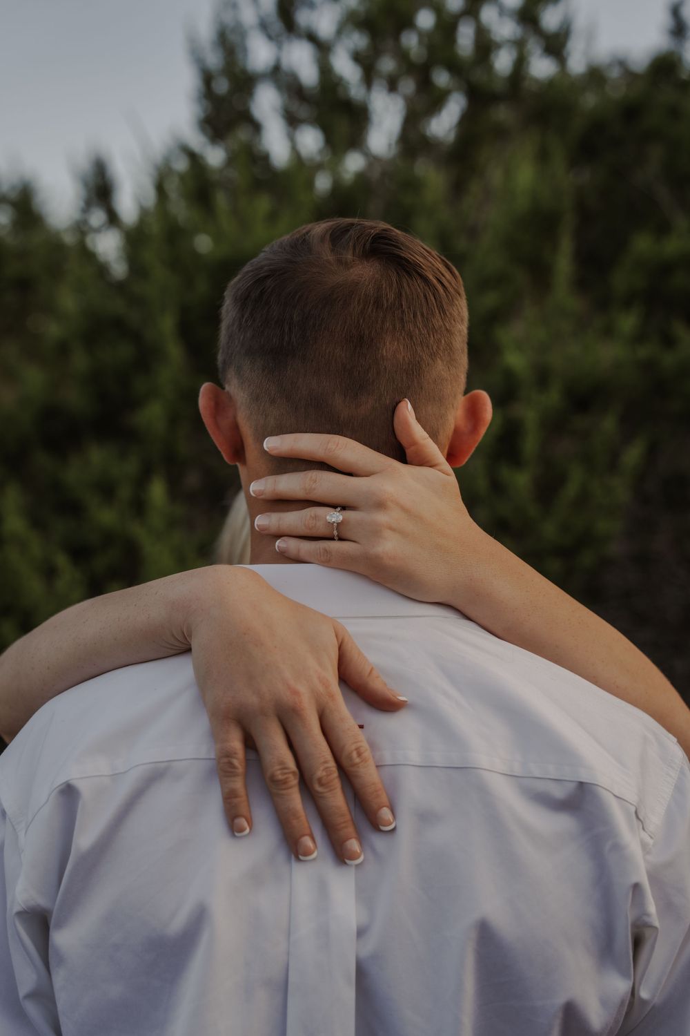 Close-up series showing hands with painted nails embracing someone wearing a white shirt from behind.