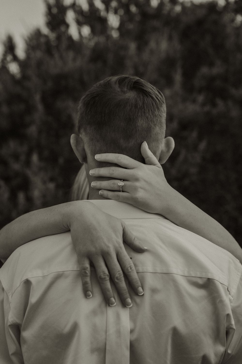 Black and white sequence of hands with a ring gently holding the back of someone in a light colored shirt.