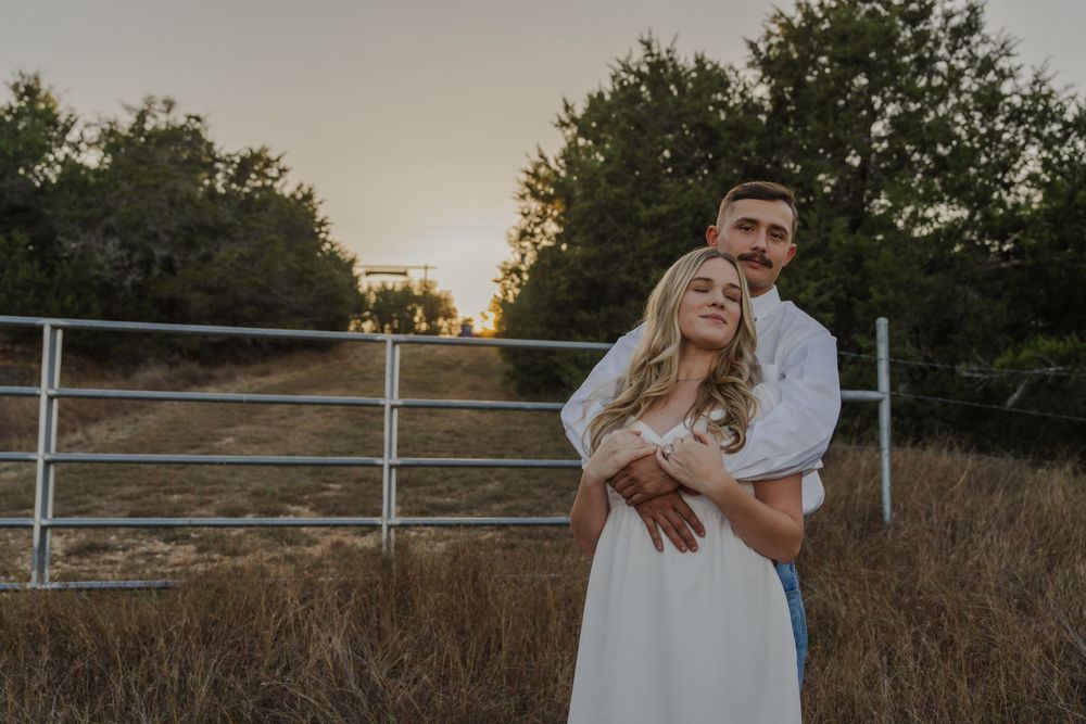 Golden hour engagement photos with couple embracing near metal gate in tall grass.