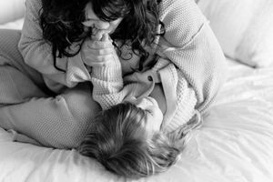 A couple sharing an intimate moment while lying together on white bedding.