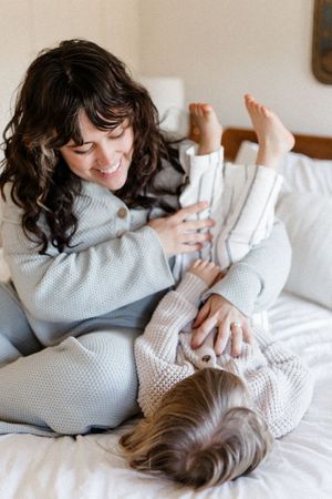 Intimate lifestyle photos showing joyful interaction between two people on white bedding.