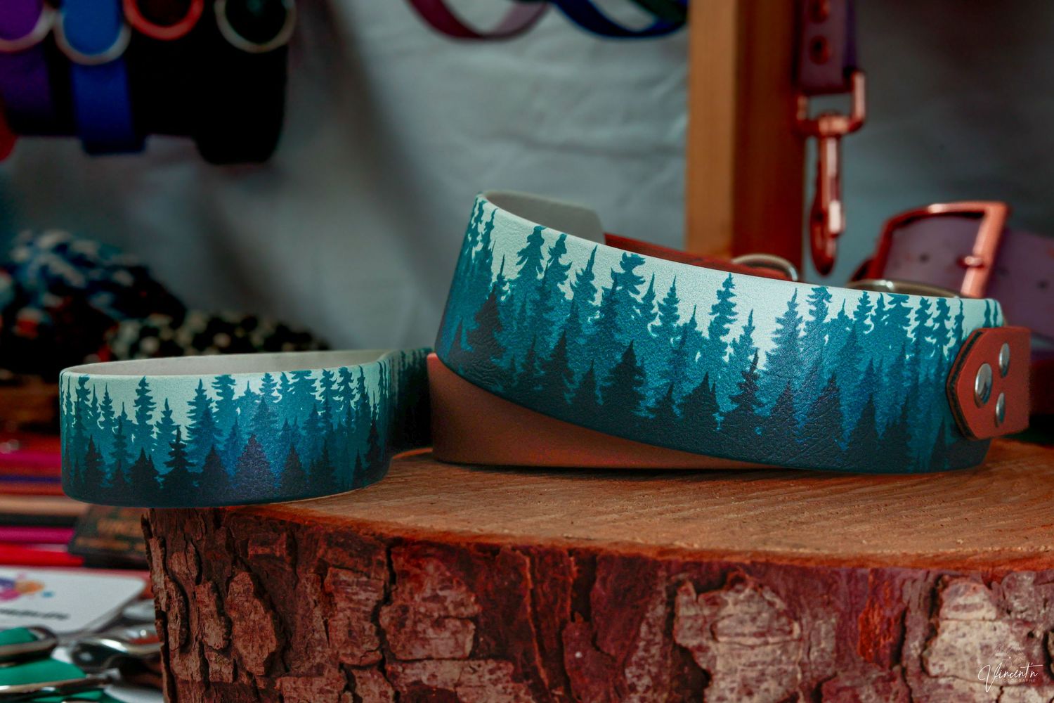 Two turquoise ceramic bowls featuring pine forest silhouettes displayed on a rustic wood slice.