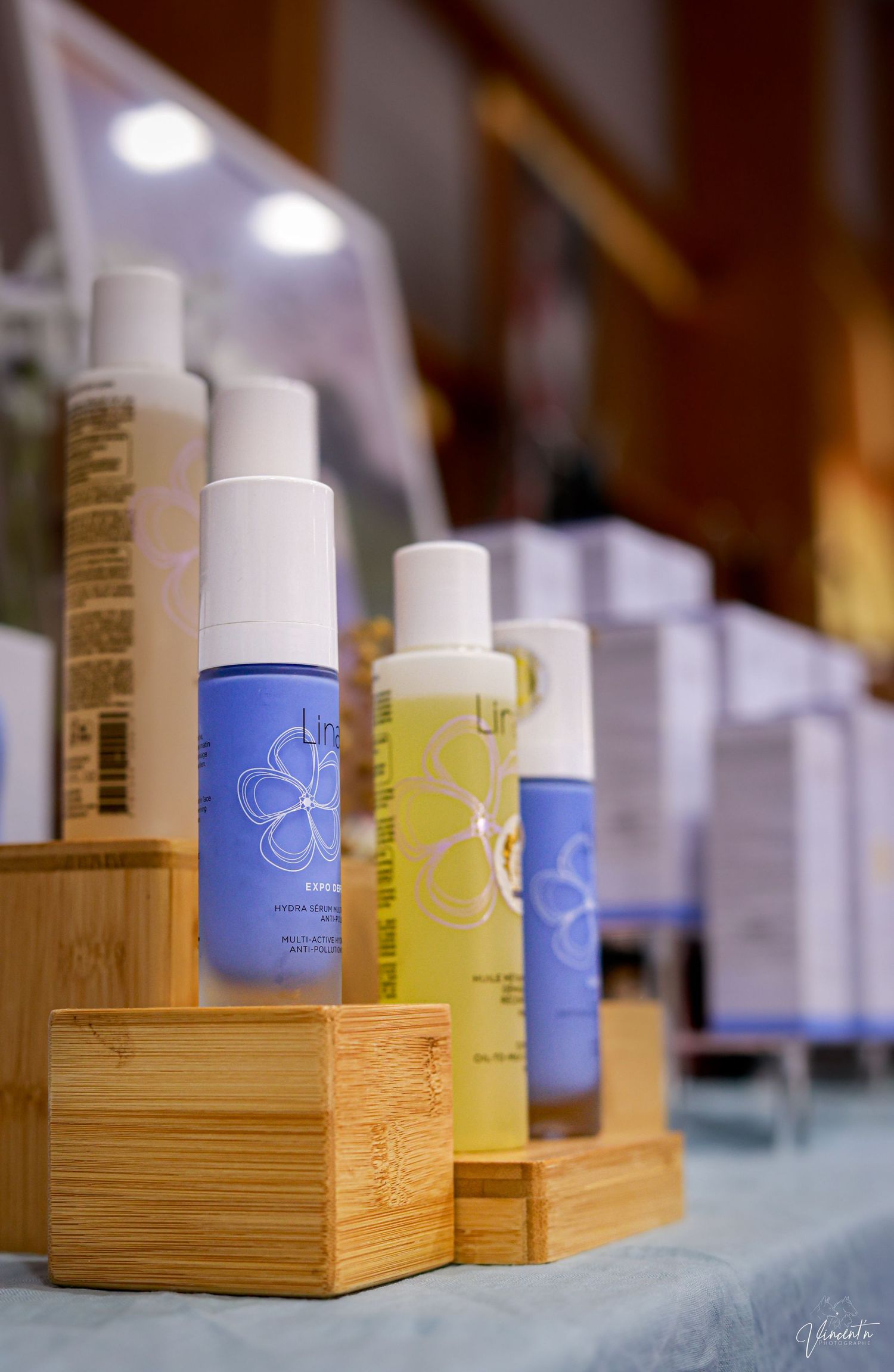 Row of skincare products in blue and yellow bottles displayed on wooden bamboo stands.