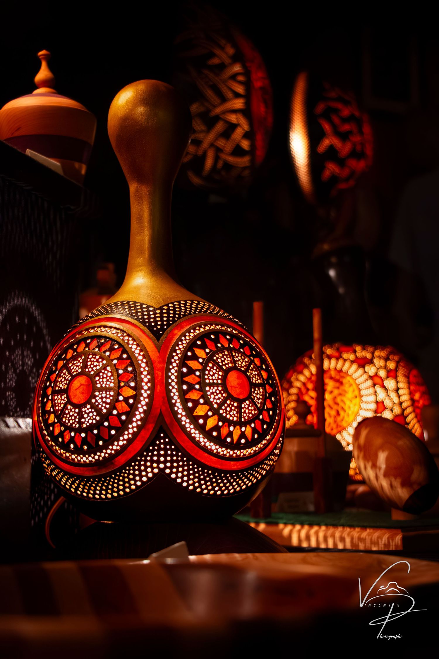 Illuminated decorative gourd lamp with intricate circular patterns casting warm orange light in darkness.
