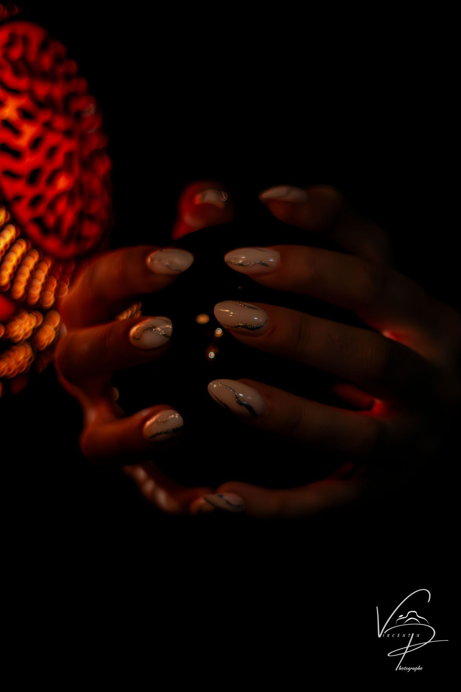 Hands gently touching a illuminated carved gourd in low light conditions.