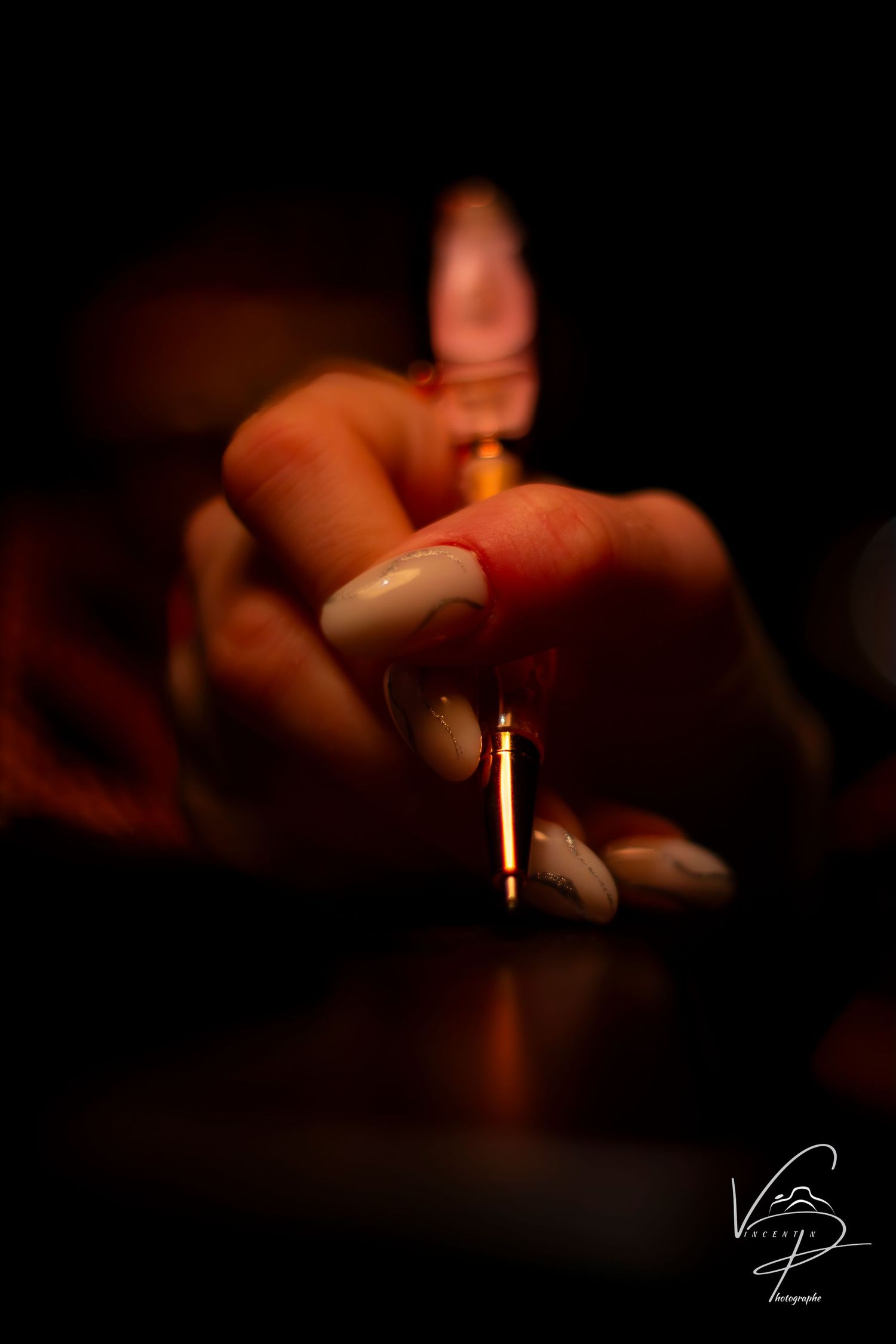 Glowing candle flame casting soft light on fingers in dark atmospheric setting.