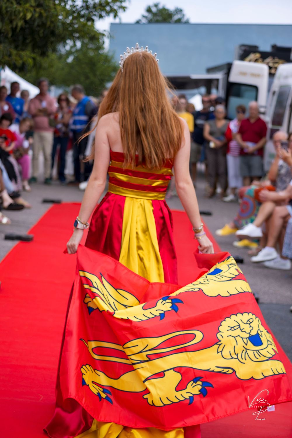 Red cape with golden lion emblem billows dramatically outdoors.