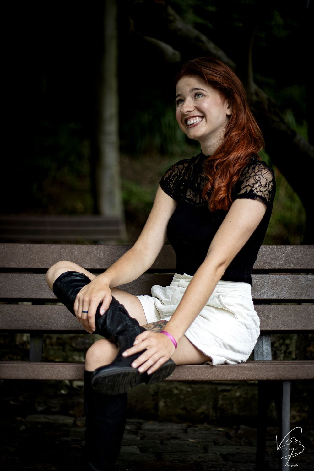 Night photography session on a wooden bench showing candid laughter and natural poses.