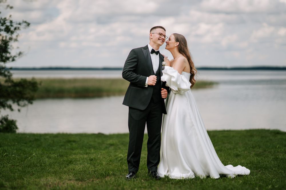 Wedding couple embracing by lakeside on their special day.